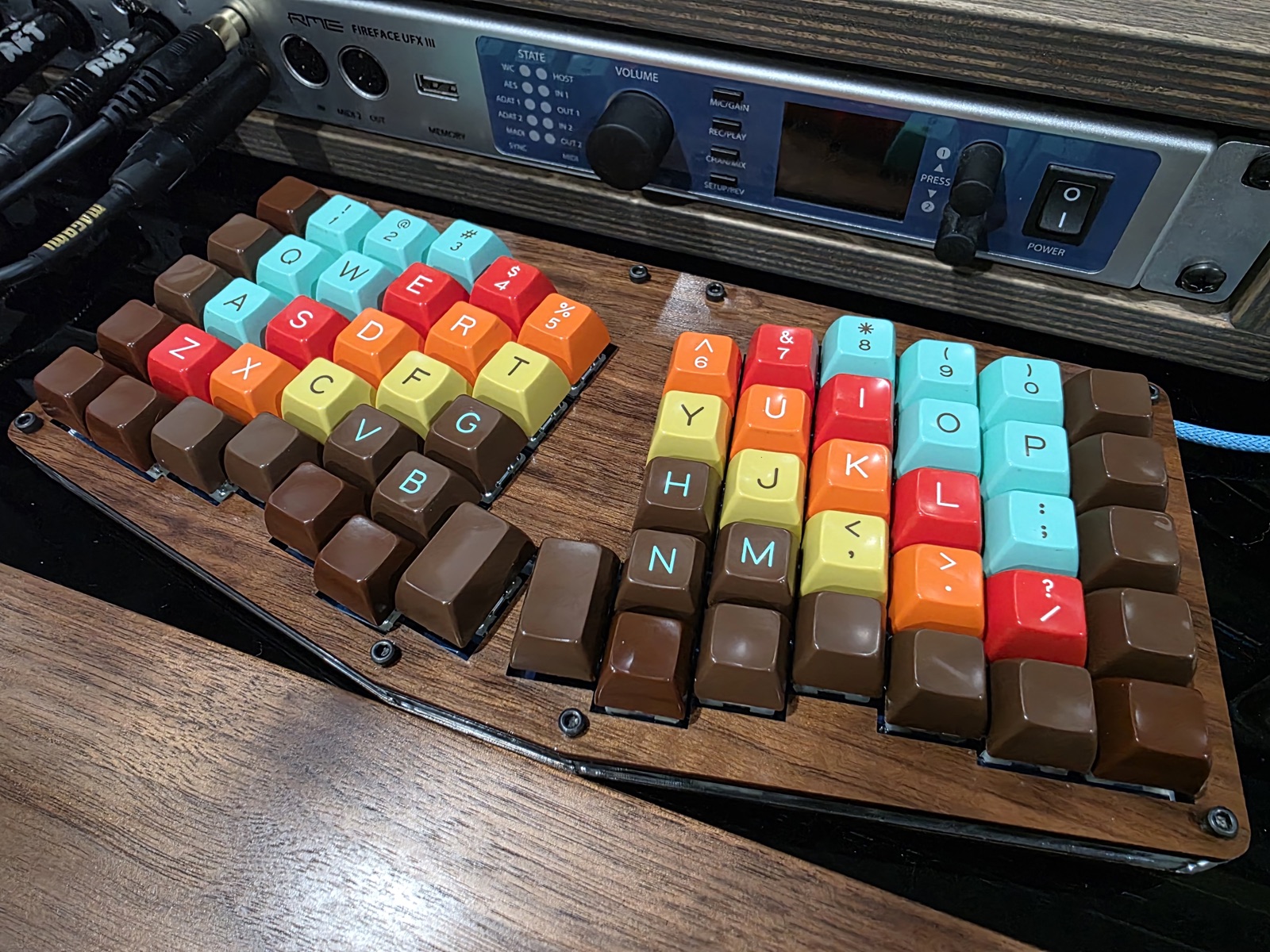 The reassembled keyboard back on the desk, colorful keycaps in place, next to audio gear