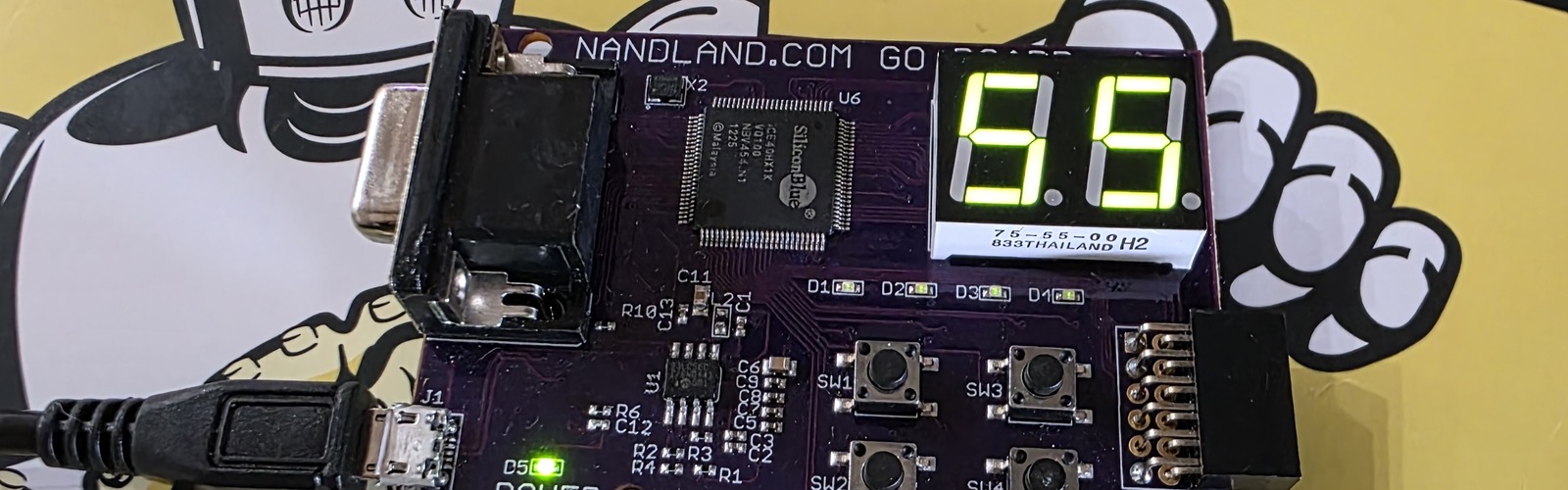 Nandland Go Board with both seven-segment displays showing '55' — the byte received over UART after typing 'U' in a serial terminal — with the Lattice iCE40HX1K chip and NANDLAND.COM GO BOARD silkscreen visible